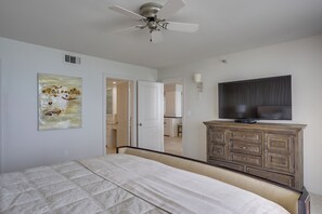 Ein Schlafzimmer mit einem Bett, einem Deckenventilator, einem Fernseher und einem Schrank.