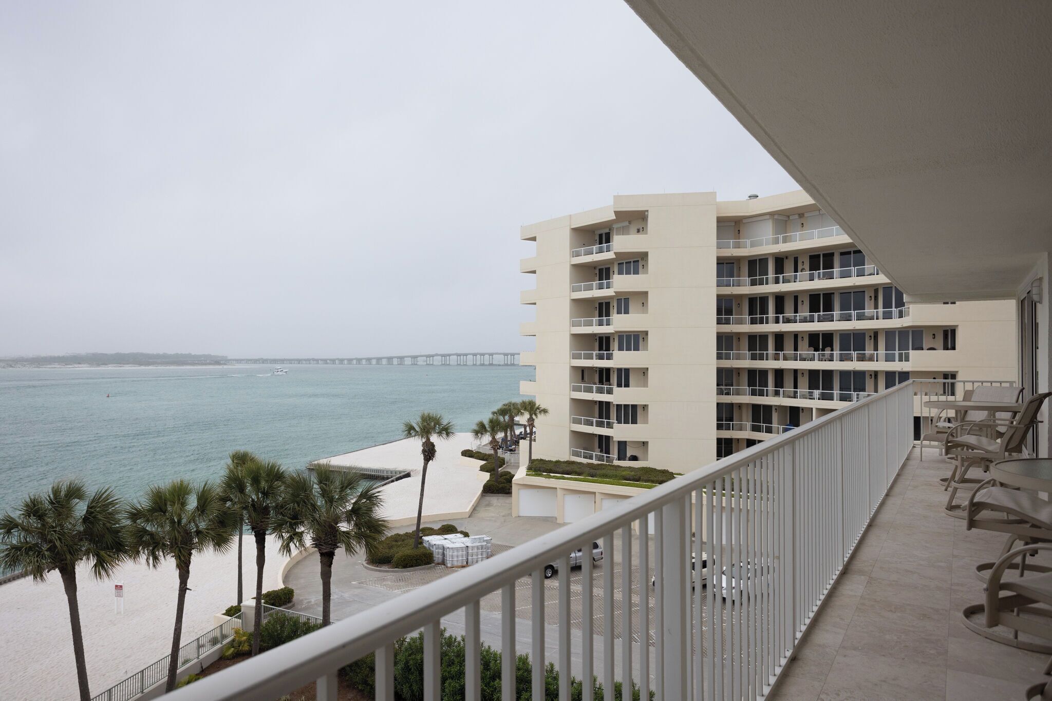 Ein Strandhotel mit mehreren Balkonen, Blick aufs Meer und einem Pier in der Ferne.