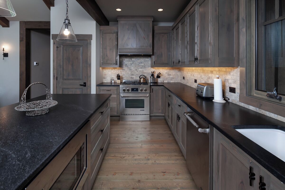 Una cocina moderna con gabinetes de madera oscura, una isla central y electrodomésticos de acero inoxidable.