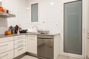 A modern kitchen with white cabinetry, a stainless steel dishwasher, and a granite countertop. - Vive y trabaja wifi rápido Barcelona Sagrada Metro (Barcelona)