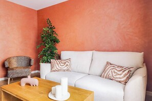A living room with a white sofa, patterned armchair, a wooden coffee table, and a potted plant. - Vive y trabaja wifi rápido Barcelona Sagrada Metro (Barcelona)
