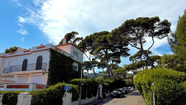 A street with a building featuring a balcony and a row of parked cars. - Cap d'Antibes, view of La Garoupe beach – Sleeps 8 – Garden and terrace (Antibes)