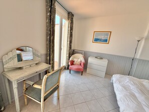 A room with a bed, a desk with a chair, a bedside table, a radiator, and a framed picture on the wall. - Cap d'Antibes, view of La Garoupe beach – Sleeps 8 – Garden and terrace (Antibes)