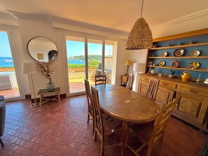 A dining area with a view of the sea, a round mirror, and a shelf with decorative plates. - Cap d'Antibes, view of La Garoupe beach – Sleeps 8 – Garden and terrace (Antibes)