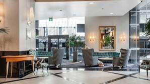 A lobby with a seating area, a reception desk, and a large mirror. - Queen Street Gem - Freshly Renovated Studio (Auckland CBD)
