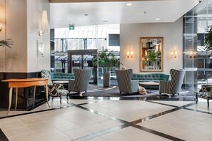 A lobby with a seating area, a reception desk, and a large mirror. - Queen Street Gem - Freshly Renovated Studio (Auckland CBD)