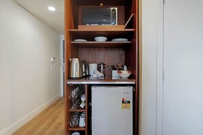 A compact kitchenette with a microwave, kettle, and small refrigerator. - Queen Street Gem - Freshly Renovated Studio (Auckland CBD)