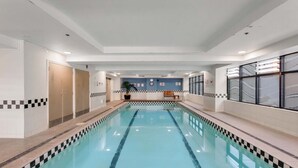 A swimming pool with a checkered border, a bench, and a wall with a clock and signs. - Queen Street Gem - Freshly Renovated Studio (Auckland CBD)