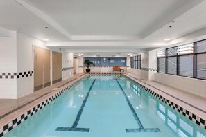 A swimming pool with a checkered border, a bench, and a wall with a clock and signs. - Queen Street Gem - Freshly Renovated Studio (Auckland CBD)