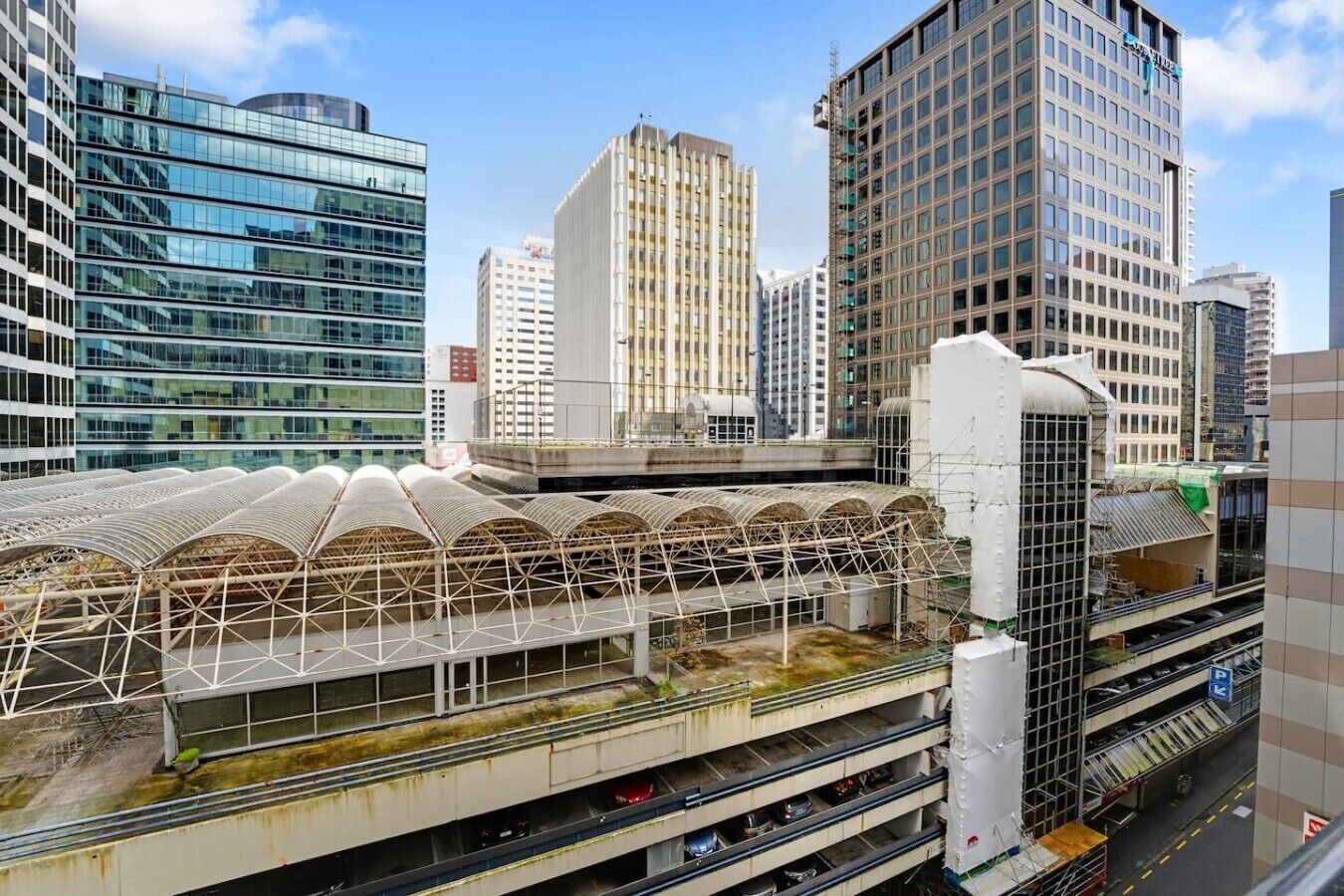 A modern urban train station with multiple tracks and a covered pedestrian walkway.