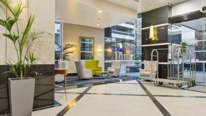 A hotel lobby with a reception desk, seating area, and a view of the outside. - Queen Street Gem - Freshly Renovated Studio (Auckland CBD)