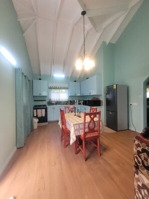 A compact kitchen with light blue cabinets, a dining table with chairs, and a refrigerator. - Cozy 2-bedroom house in perfect Mesopotamia with AC (Mesopotamia)