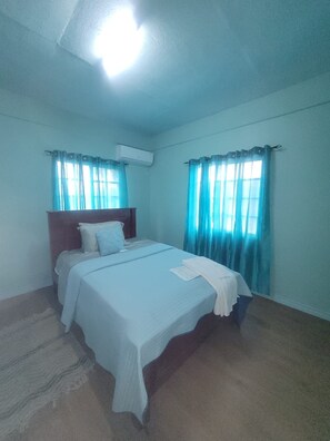 A bedroom with a bed, curtains, an air conditioning unit, and a carpeted floor. - Cozy 2-bedroom house in perfect Mesopotamia with AC (Mesopotamia)