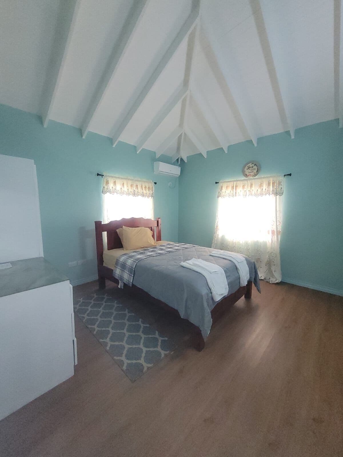 A bedroom with a bed, a nightstand, and a window with curtains.
