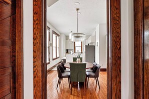 A dining area with a round table, chairs, and a hanging light fixture. - Amber & Oak: Theater, Game Room & Fire Pit (Omaha)