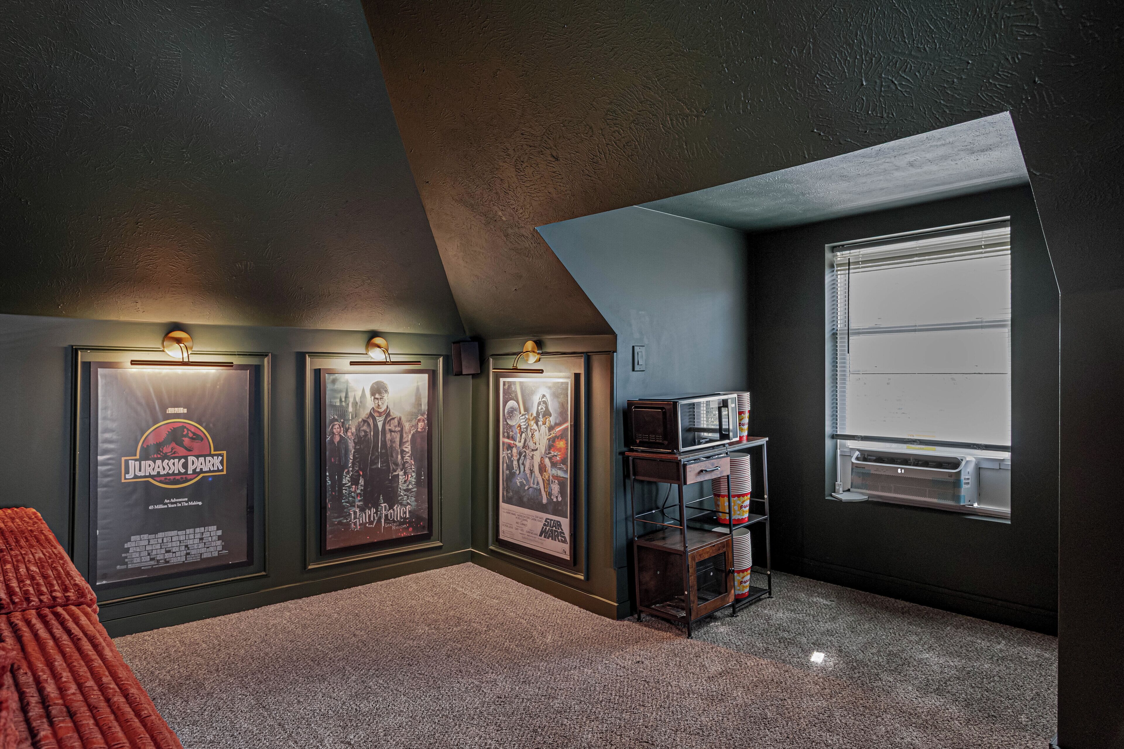 A room with a sloped ceiling, a window, and posters on the wall.