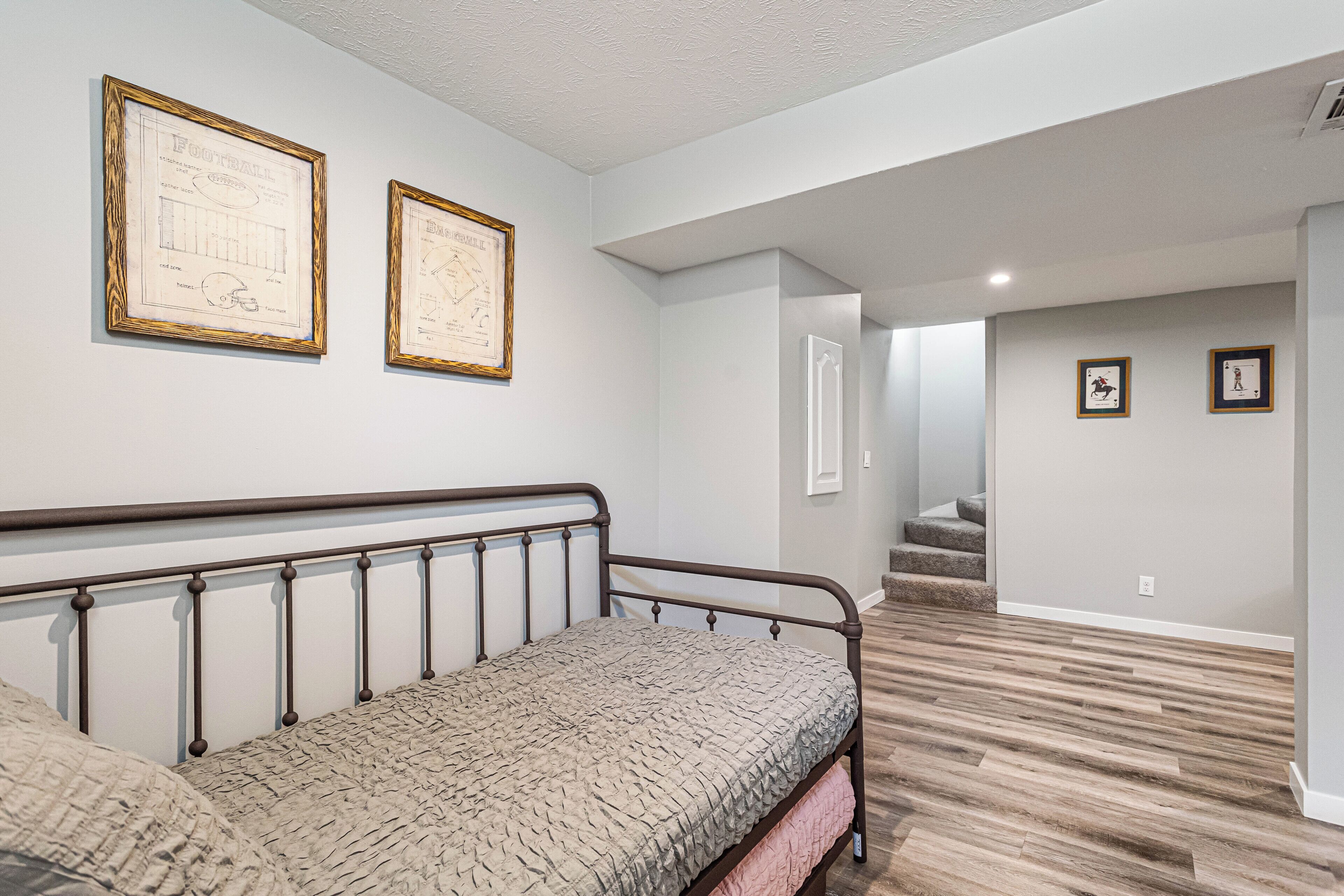 Ein Schlafzimmer mit einem Bett, einem gerahmten Bauplan an der Wand und einer Treppe, die in einen anderen Raum führt.