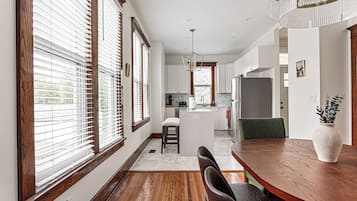A modern kitchen with a central island, wooden flooring, and a dining area with a table and chairs.
