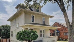 A two-story house with a front porch and a small front yard. - Amber & Oak: Theater, Game Room & Fire Pit (Omaha)