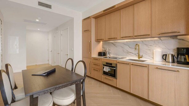 Una cocina moderna con armarios de madera, encimera de mármol y horno empotrado.