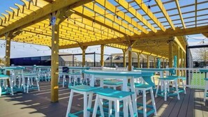 An outdoor seating area with wooden pergola and tables. - Bethany Beach Retreat sleep7 Pools, Pickleball, & Shuttle (Millville)