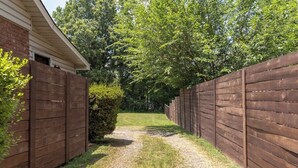 Un sendero de grava bordeado por vallas de madera que conduce a una casa de ladrillo.