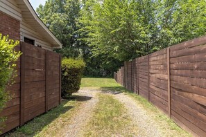 A gravel path flanked by wooden fences leading to a house with a brick exterior. - Renovated 3BR House - Monthly Stays - Fenced Quarter-Acre Yard - Pets Welcome (Charlotte)