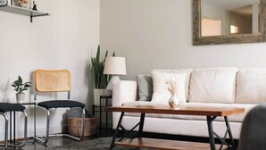 Una sala de estar con un sofá, una mesa de centro, una lámpara y una silla.