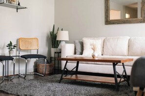 A living room with a sofa, a coffee table, a lamp, and a chair. - Renovated 3BR House - Monthly Stays - Fenced Quarter-Acre Yard - Pets Welcome (Charlotte)