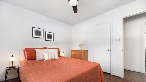 Un dormitorio con cama, mesitas de noche, cómoda y una puerta.