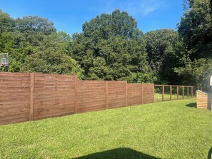 A fenced backyard with a wooden structure and a grassy lawn. - Renovated 3BR House - Monthly Stays - Fenced Quarter-Acre Yard - Pets Welcome (Charlotte)