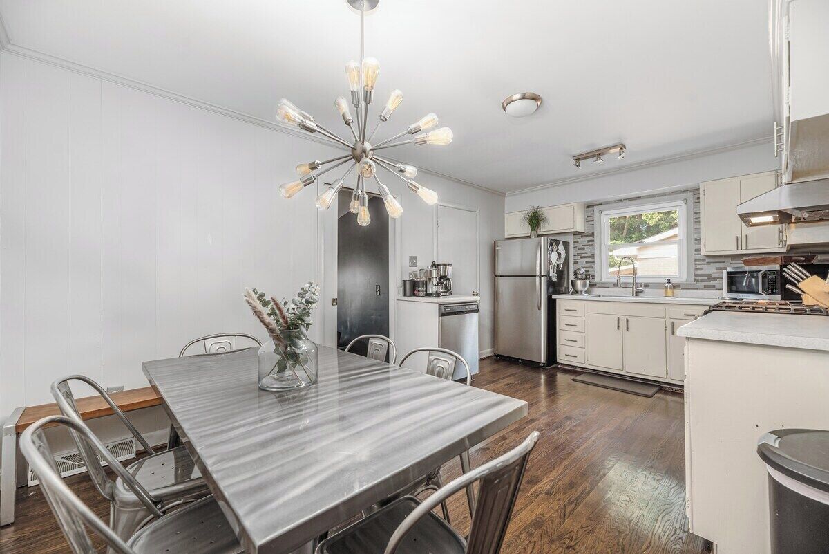 A modern kitchen with a central island, stainless steel appliances, and a dining area with a marble table.