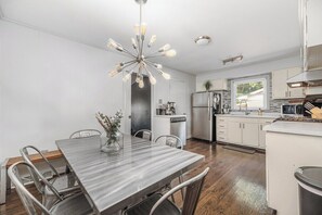 A modern kitchen with a central island, stainless steel appliances, and a dining area with a marble table. - Renovated 3BR House - Monthly Stays - Fenced Quarter-Acre Yard - Pets Welcome (Charlotte)