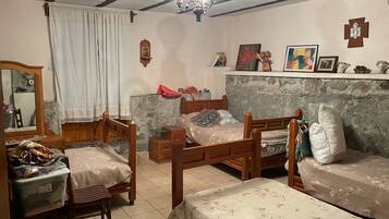 A room with a bed, wooden furniture, a mirror, and a wall with religious symbols.