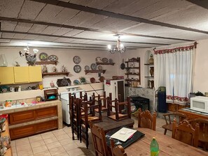 A kitchen with wooden cabinets, a dining table, chairs, and various kitchen appliances.