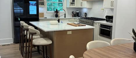 A modern kitchen with a central island, bar stools, and pendant lighting.