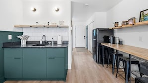 Et moderne køkken med en central ø, et spiseområde med barstole og en træbordplade.