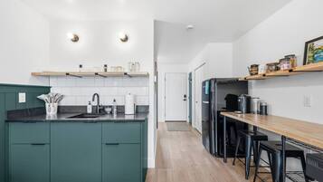 A modern kitchen with a central island, a dining area with bar stools, and a wooden countertop.