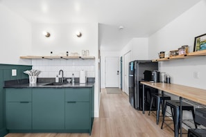 A modern kitchen with a central island, a dining area with bar stools, and a wooden countertop. - New! Style & Harbor Views | Walk to Food & Tours (Juneau)