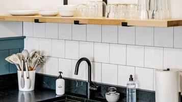 A kitchen with a black faucet, a soap dispenser, and a glass container on the counter.