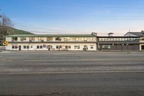 A two-story building with a flat roof, a storefront on the ground floor, and a parking lot in front. - New! Style & Harbor Views | Walk to Food & Tours (Juneau)