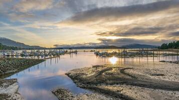 A marina with boats docked, calm water, and a sunset in the background.