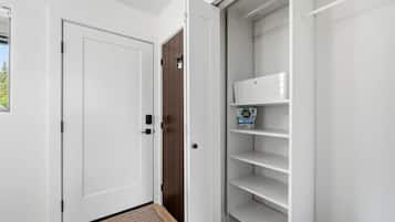Un couloir avec une porte blanche, une porte marron et une étagère blanche contenant une boîte de lessive.