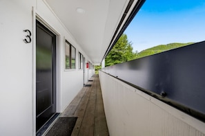 Un couloir avec une porte numérotée 3, des fenêtres et une vue sur la verdure.