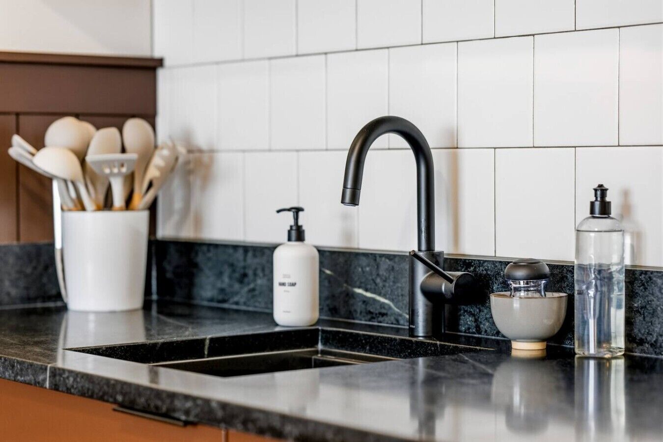 A kitchen with a black faucet, a soap dispenser, and a glass container on the counter.