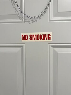 A door with a 'NO SMOKING' sign and a chain-link security barrier. - Cozy 1-bedroom studio in soothing Virginia Gardens with AC (Virginia Gardens)