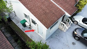 A residential building with a red-tiled roof, a white exterior, and a visible garage door. - Private studio with its own entrance, minutes from MIA. Parking at the door (Virginia Gardens)