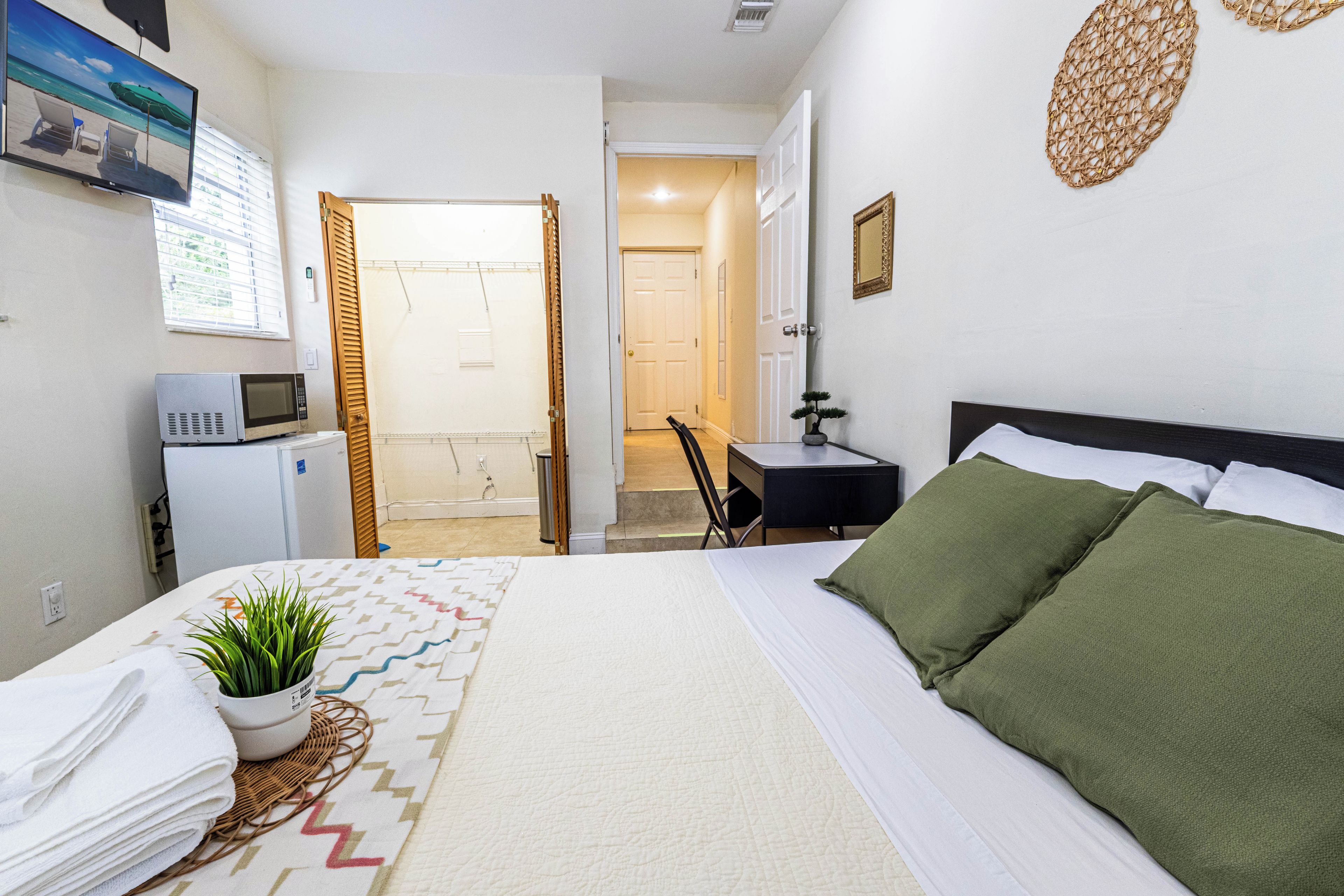 Une chambre d’hôtel équipée d’un lit, d’un bureau, d’une chaise, d’un four à micro-ondes et d’un petit réfrigérateur.