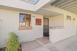 A residential building with a number '4042' on the wall, a window with blinds, a small outdoor step, and a door with a metal gate. - Bright Golf View Villa: Vaulted Ceilings, Patio Dining, Mtn Views & Resort Pool (Palm Desert)