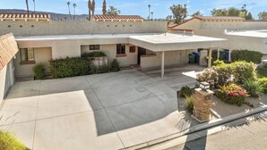 A residential building with a flat roof, multiple windows, and a paved courtyard. - Bright Golf View Villa: Vaulted Ceilings, Patio Dining, Mtn Views & Resort Pool (Palm Desert)